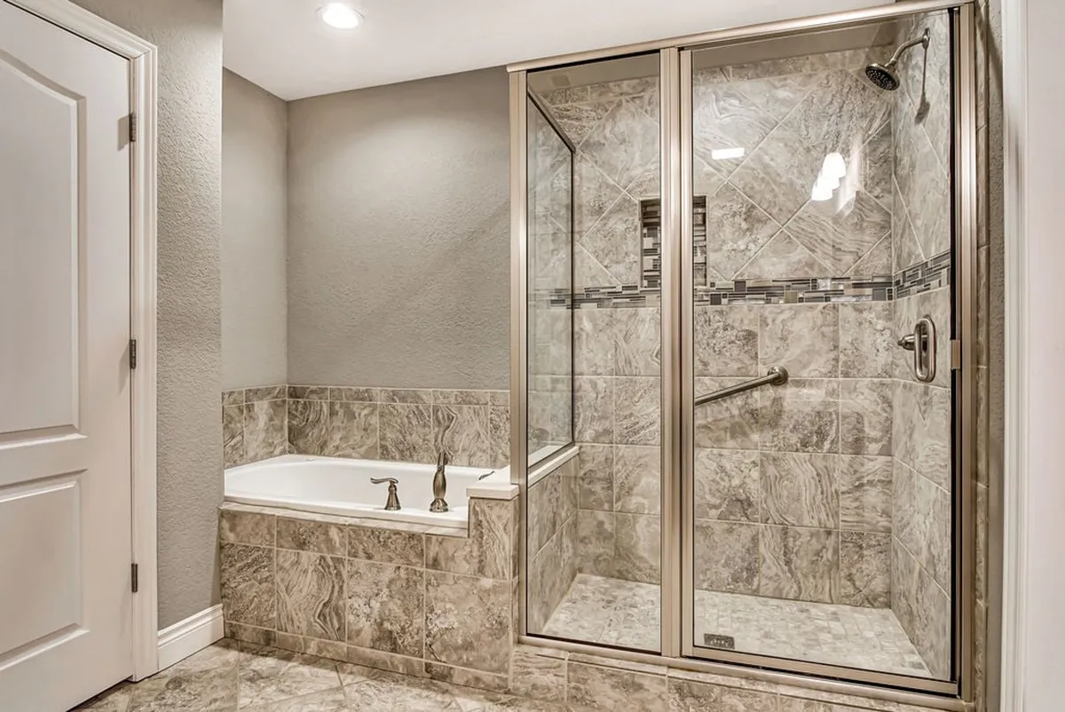 A tranquil, spa-inspired bathroom featuring a deep soaking tub, a glass-enclosed walk-in shower, elegant tile work, and premium fixtures. The space is spacious, bright, and designed for relaxation and self-care routines.
