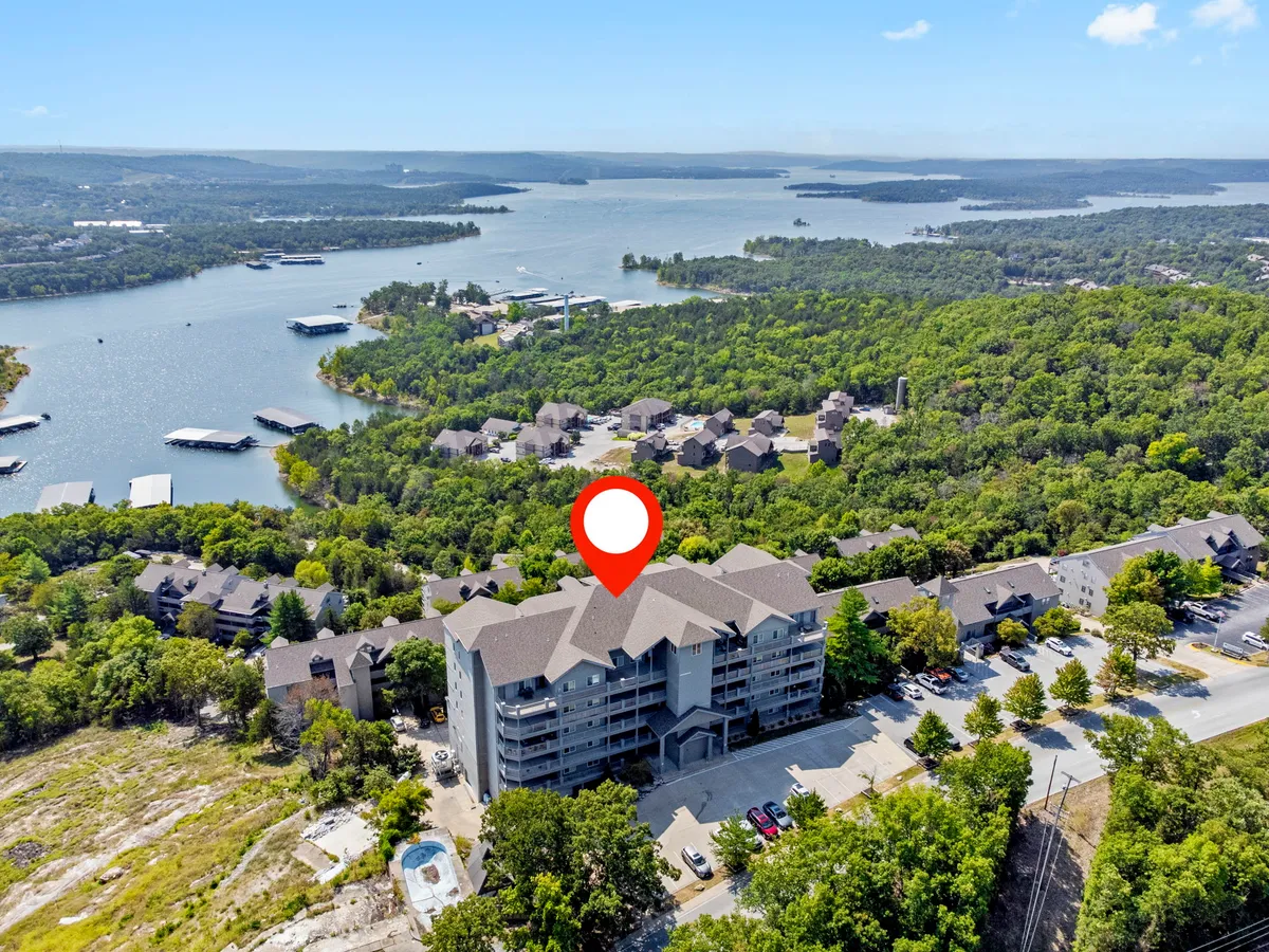 A sweeping exterior view of Table Rock Lake as seen from a peaceful vantage point, with lush greenery surrounding the lake and the attractive building architecture visible. The warm tones suggest either sunrise or sunset, capturing the tranquil beauty and romance of the lakeside setting.