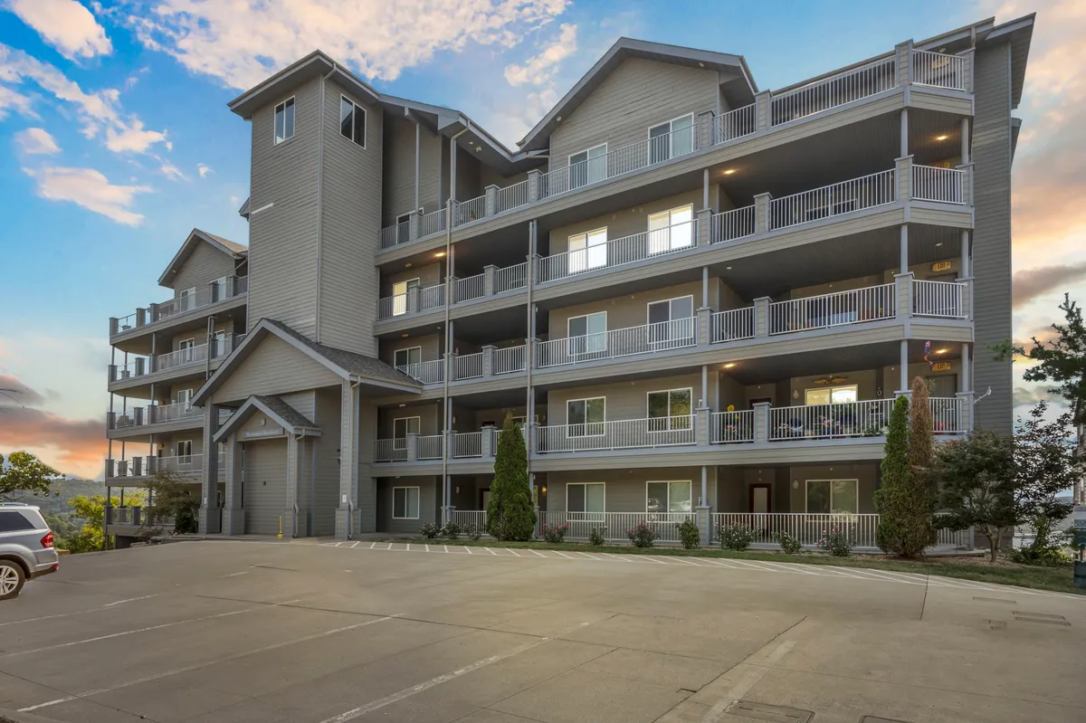 This exterior shot highlights the main building facade, with welcoming balconies overlooking lush landscaping. The image conveys a sense of connection with the outdoors and invites viewers to imagine relaxing while taking in sunset views or watching for wildlife from the comfort of their private outdoor space.