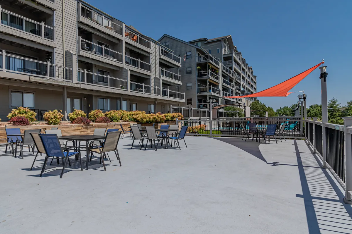 A vibrant outdoor seating area under a canopy, surrounded by colorful plants. The arrangement hints at group gatherings, outdoor dining, or relaxing after exploring local attractions. The mood is cheerful and sociable, with plenty of space for friends to gather.