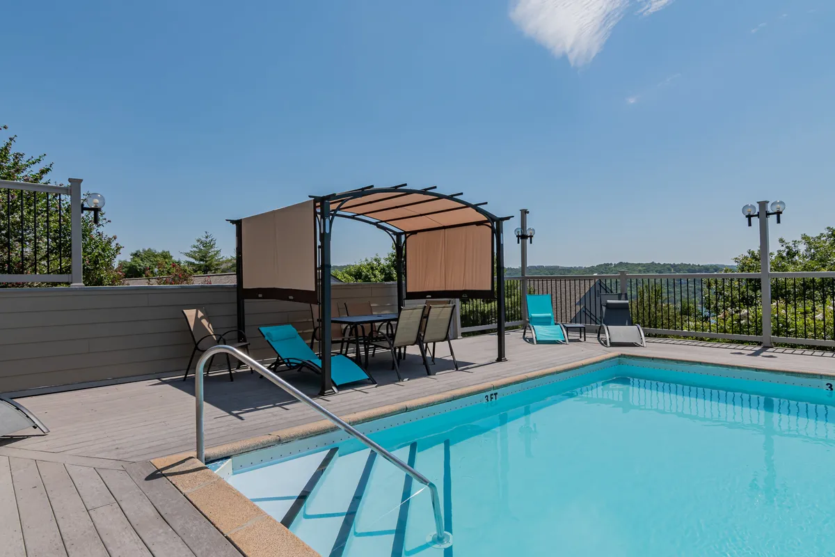 A vibrant outdoor pool area is shown, featuring a swimming pool, canopy, and ample lounge chairs for sunbathing or relaxing. The setting is lively yet peaceful, offering a glimpse of where guests can cool off or unwind after a day exploring the lake and trails.